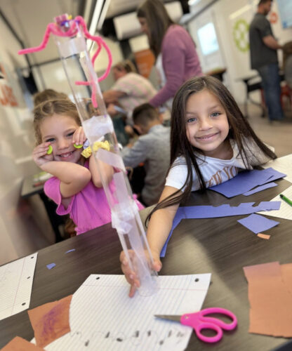 third grader students smile with their engineering design challenge tower