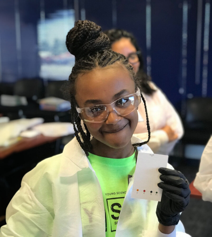 girl in safety goggles happy with her lab test results