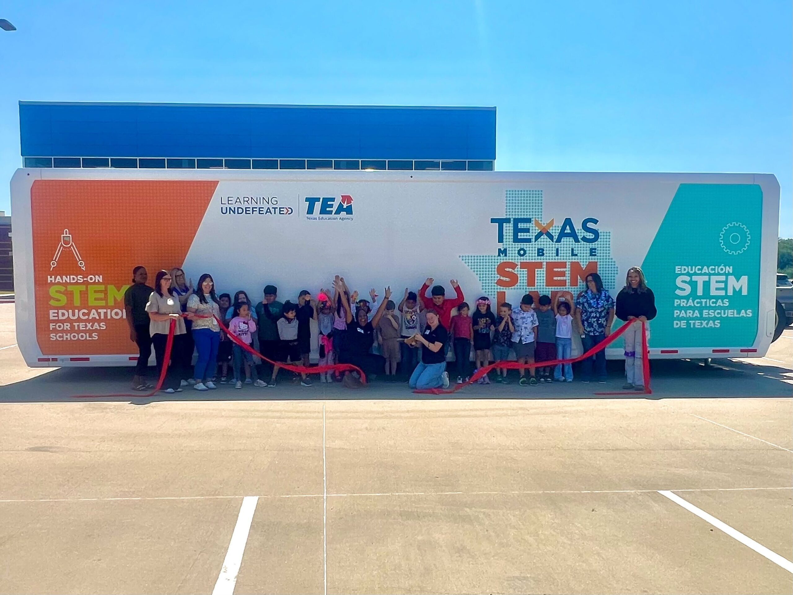 a group of people holding a ribbon cutting event at the Texas Mobile STEM Lab