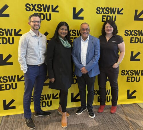 four people standing in front of a sign